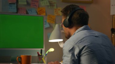 Evde müzik dinleyen sakallı adam. Olumlu bağımsız yazar favori şarkılarını yazarken bilgisayardan keyif alıyor. Arka planda dans eden adam, gece apartmanında iş yerinde ritmik bir şekilde dans ediyor.