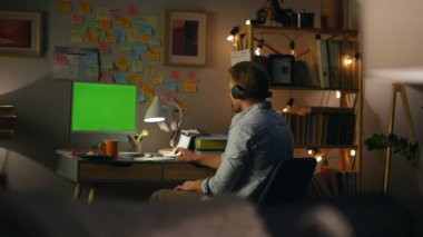 Evde yakın planda serbest dans eden pozitif bir sandalye. Genç adam uzaktan kumandalı yeşil ekranda ritmik şarkılar dinliyor. Kulaklıklı adam bilgisayarın yanında müzik dinleyip eğleniyor. İnsan yaşam tarzı