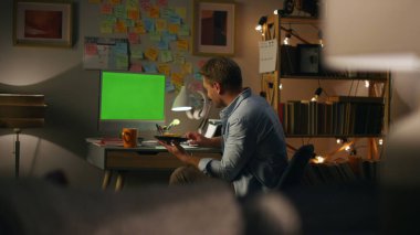 Sakallı adam, yakın çekimde masayı selamlıyor. Yeşil ekranı gösteren adam bilinmeyen eşiyle konuşuyor. Geceleri Chromakey PC sallayan pozitif serbest çalışan. Bilgisayar masasında sandviç yiyen bir erkek.