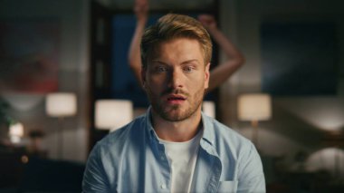 Düşünceli serbest çalışan video sohbeti. Uzaktan yakından. Rahat bir iş yerinde dizüstü bilgisayar izleyen sakin bir adam. Karısının siluet dansı geçmişi. Fazla çalışan adam gerekli görevi tartışıyor.