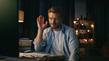 Mutlu adam el sallıyor. Neşeli uzman yalnız gece dairelerinde görüntülü arama yapıyor. Memlekette serbest çalışan, sohbet eden pozitif bir iş arkadaşı. Gülümseyen adam görüntülü konuşma yapıyor.