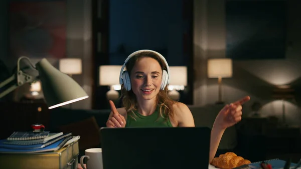 Festive person dancing home closeup. Modern girl working laptop at night flat closeup. Excited woman spending evening at cozy apartments. Young headphones woman listening enjoying energetic music