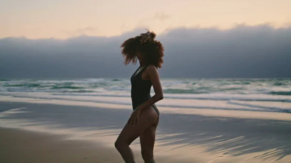 非裔美国女孩在阴暗的海滨跳舞 柔韧的年轻女子平稳地移动着身体 享受着多风的暮色 卷曲的黑发表演当代自然风格 — 图库照片
