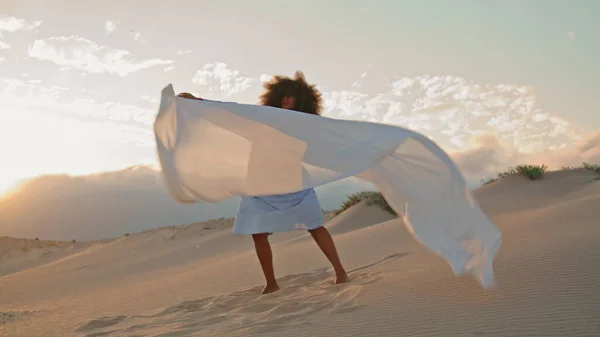 性感的女舞蹈演员挥动着飘扬的白布 在夏天的沙漠中表演当代舞蹈 日落时分 卷曲的非洲裔美国女人在沙丘上跳舞 身上撒满了布料 布鲁内特表演艺术家 — 图库照片
