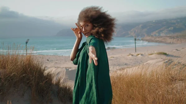 迷人的舞女手握着手平稳地站在沙地沙丘边 草叶干枯 非洲裔美国女孩在大自然中表演时 镜头就近 夏日的风吹拂着乌黑的卷发 — 图库照片