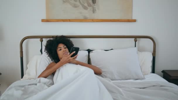 Модель Чтения Смартфона Люксовая Спальня Кудрявая Женщина Отдыхает Белом Интерьере — стоковое видео