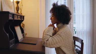 Ciddi kadın vintage masada çalışıyor. Evde ekranı izleyen dizüstü bilgisayarı daktilo eden serbest çalışanı kapat. E-posta gönderen Afrikalı Amerikalı kız mali raporu uzaktan hazırlıyor