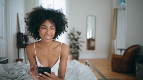 Mulher Sorridente Mensagens Smartphone Quarto Cabelo Encaracolado Rindo Senhora Sms — Vídeo de Stock