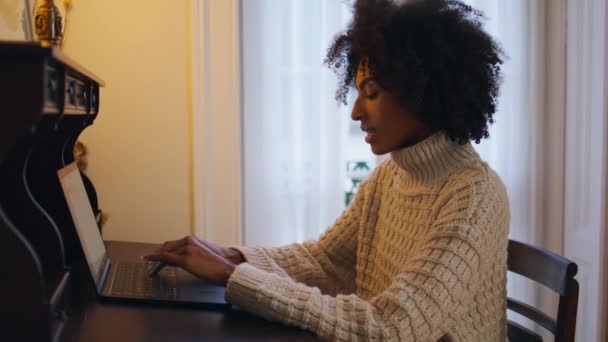 木製の机の職場でインスピレーションを受けたモデルのテキストノートパソコン かわいい髪の笑顔の女性のソーシャルネットワークでの電子メールの手紙を閉じるに答えるチャット アフリカの正の女性は アパートでコンピュータボタンを押す — ストック動画