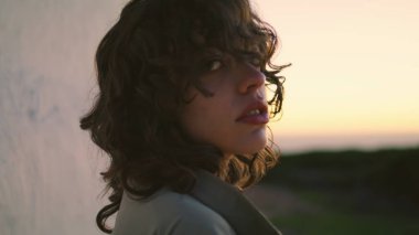 Dark silhouette turning head at beautiful sunset sky closeup. Smiling girl look camera enjoying evening outdoors. Attractive lonely female thinking personal life problems at night. Serene calm person.