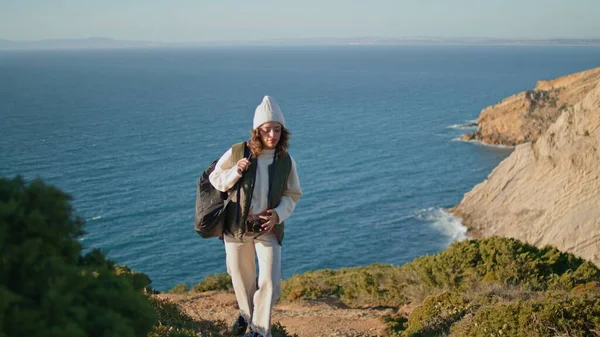 Hiker traveling ocean mountain on spring vacation. Smiling girl taking picture admiring beautiful sea view. Carefree tourist woman trekking with backpack enjoying weekend. Tourism adventure concept.