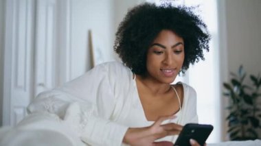 Otel kapanışında akıllı telefonları dinlemenin mutluluğu. Esmer tenli, gülümseyen kadın yeni cep telefonu uygulamasını test ediyor. Afrika 'lı neşeli bir kadın internette cep telefonunu tek başına kullanıyor.