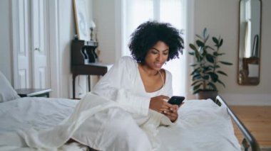 Gülümseyen bayan yatak odasında akıllı telefon mesajı atıyor. Kıvırcık saçlı kadın, White Hotel 'in içindeki cep telefonuyla mesaj atıyor. Afrika kökenli Amerikalı kız sosyal ağların cihaz iletişiminin tadını çıkarıyor.