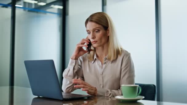 认真的企业家在办公室里讲手机 在现代工作场所给成功的女商人打电话 自信的主管打电话到笔记本电脑桌前摆姿势 — 图库视频影像