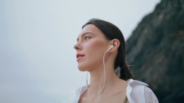 Портрет Красивой Молодой Женщины Современных Наушниках Слушающей Музыку Облачном Пляже — стоковое видео