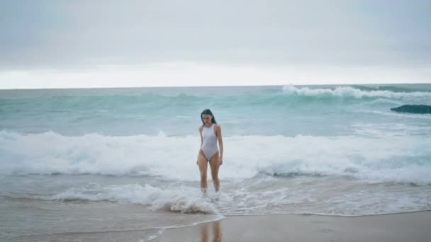 穿着雅致的白色泳衣的成熟的赤脚女人走出去 迷人的身材苗条的女孩在狂风暴雨的海面上散步 周末阴云密布 年轻性感的女士在海滨暑假放松一下 — 图库视频影像