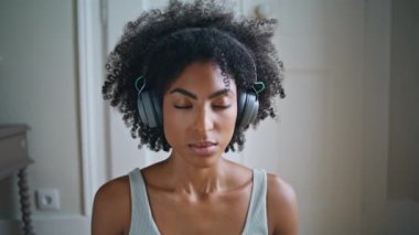 Yoga yapan kadın hava beyaz odasını içine çekiyor. Sakin genç bayan derin nefes alıyor. Gözleri kapalı meditasyon yapıyor. Kulaklıkla yoga yapan Afrikalı sakin bir model. Huzur kavramı 