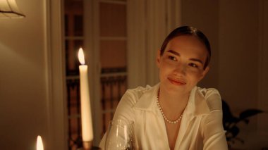 Geceleyin gülümseyen bayan romantik randevu portresi. Şık bir kadın, akşam saatlerinde şarap kadehine dokunan biriyle flört ediyor. Sıcak mumların altında dinlenen seksi kız. Yıldönümü kavramı