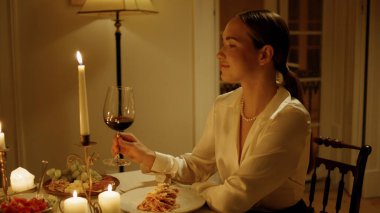 Gorgeous woman sniffing wine at candles table closeup. Seductive lady drinking grape cocktail at fancy evening dinner. Smiling girl clinking glasses tasting alcohol with unknown husband. Date concept