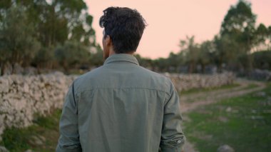 Rahatlamış adam yaz yürüyüşü doğa yakın çekim. Kırsal kesimde gezen, ilham verici yetişkin bir adam. Ciddi bir çiftçi kırsal alanda tek başına köyü yavaş yavaş keşfediyor.
