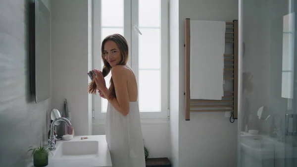 Positive Lady Arranging Hair Bathroom Interior Smiling Woman Staring Camera — Zdjęcie stockowe