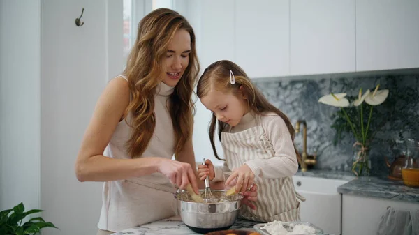 stock image Lovely woman baby cooking at kitchen together closeup. Young family preparing dough for cookies at home table. Mother daughter enjoying making pastry in modern interior. Cute child girl helping mom