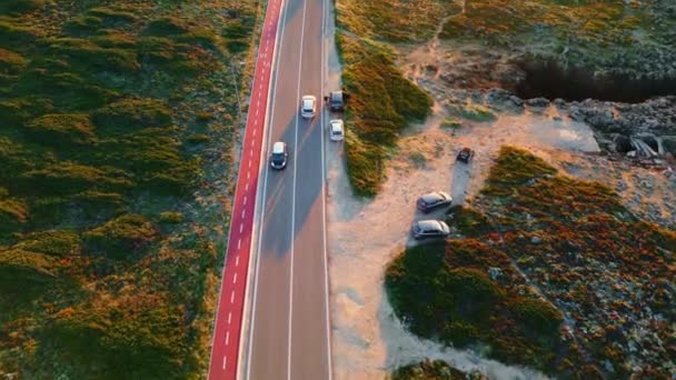 空中观光汽车在乡间路上行驶 在覆盖着绿色植被的石质地形上匆忙运输的沥青路面上的无人机镜头 汽车慢速行驶在公路上 — 图库视频影像