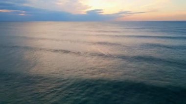 Yaz akşamından sonra güzel, bulutlu, sonsuz okyanus ufku. Hava manzarası güneş batarken deniz yüzeyini sersemletiyor. Karanlık, derin su dalgaları güneş ışığını yansıtıyor. Doğa sükuneti kavramı.