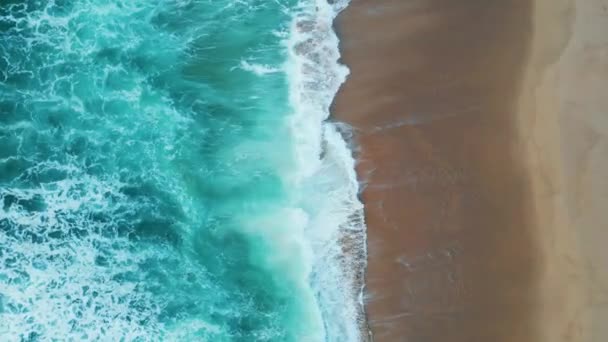 無人機は 空の熱帯のビーチの夏の日を洗うターコイズブルーの海の波を撃った 美しい海岸線の風景泡立つ海の水の美しい海岸の遅い動きに圧延 風光明媚な海岸に白い泡が飛び散る — ストック動画