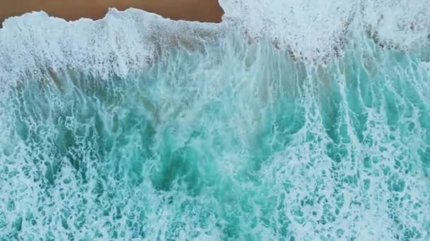 ターコイズブルーの泡の海の水が砂の海岸の空中ビューに飛び散っています 美しいビーチスローモーションに圧延見事な海洋景観嵐の海の波 熱帯の風光明媚な海岸線を洗う素晴らしい海サーフィン — ストック動画