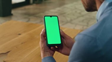 Patronun elleri kapalı mekanda akıllı telefonu tutuyor. Anonim iş adamı ofiste yalnız başına Webinar 'ı izlerken mesaja zum yapıyor. Bilinmeyen girişimci Chroma anahtar telefon kullanarak lobi alanında oturuyor