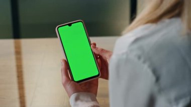 Kullanıcı kromakey akıllı telefonu kapalı mekanda yakına çekiyor. Ofiste el ele tutuşan bir kadın. Yeşil ekran cep telefonu kullanan tanınmamış zarif bir iş kadını. Lüks iş kadını internette sörf yapıyor. 