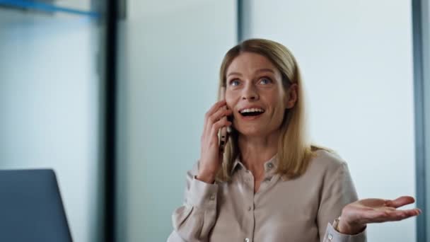令人惊讶的女人不知道智能手机在工作场所关闭 在现代办公室里 在手机聊天时 微笑着的创业者在感情用事 兴奋的女士在室内打电话 成功概念 — 图库视频影像