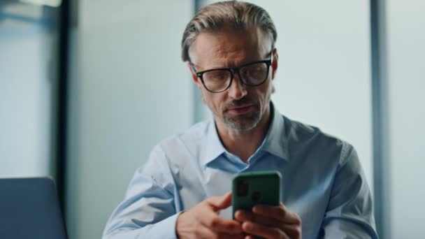 有思想的人在办公室的肖像工作电话 在笔记本电脑的特写镜头上 有重点的商人输入智能手机电子邮件检查工作项目 眼镜老板在现代工作场所浏览移动多任务 — 图库视频影像