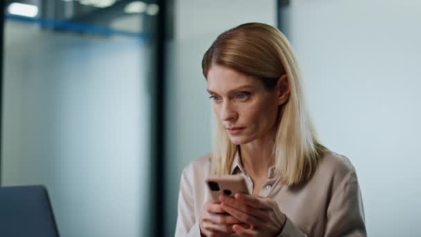 여성분 내각에서 휴대폰 문자를 있습니다 컴퓨터 테이블에 스크린을 집중적 스마트폰으로 — 비디오