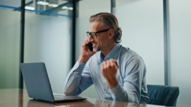 Neşeli kazanan kabinede telefonla konuşuyor. Neşeli iş adamı cep telefonu konuşmasında zafer kazanıyor. Heyecanlı menajer iş arkadaşıyla yaptığı sohbeti kutluyor. İş anlaşması konsepti