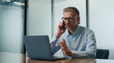 Ofiste cep telefonundan konuşan ciddi bir iş adamı. Cam duvarların iç tarafındaki akıllı telefondan aranan başarılı bir girişimci. Gözlük direktörü kabinede el kol hareketi yapıyor. 