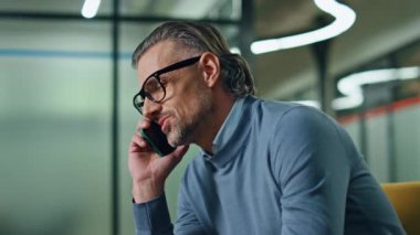 Ofisin içinde cep telefonundan konuşan kendinden emin bir iş adamı. Kanepedeki Ceo 'nun cep telefonunu aramasını işaret eden yakın plan. Sakallı müdürün ortağıyla ciddi bir telefon görüşmesi var. İş sohbeti