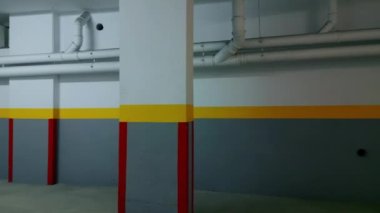 Koyu, boş bina koridoru. Gri, sarı, kırmızı renklerle boyanmış. Çimento zemini ve tavanında borular olan geniş bir sanayi koridoru. İçinde gölgeler olan terk edilmiş inşaat salonu manzarası. 