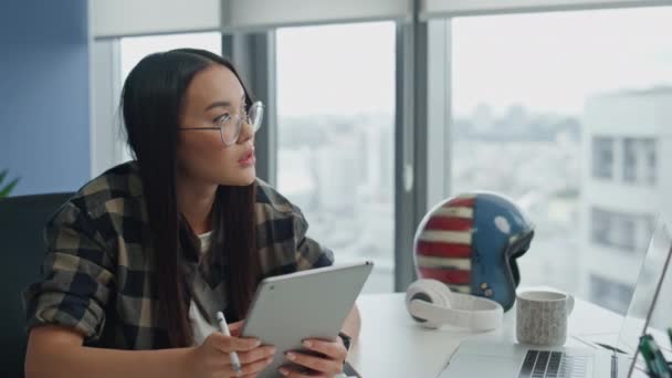リモートの職場の閉鎖で深刻なイラストレーターワーキングコンピュータ シティビューアパートのノートパソコンのタッチパッドを使用して思考のクリエイター アジアの女性は自宅のオフィスでタブレットを保持創造的な環境 — ストック動画