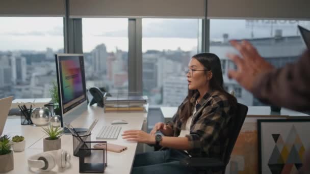 オフィスの近くで眼鏡の女性の挨拶の同僚 賢い男はコンピュータを見て助言を与える ビジネスのカップルは問題解決を見つける議論を有する テーブルでコラボレーションする若いスタートアップ — ストック動画