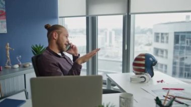Masa başında kendine güvenen bir adam el kol hareketi yapıyor. Ofiste cep telefonuyla çevrimiçi projeyi tartışan olumlu yaratıcı. Şehir manzarası işyerinde iş görüşmesi yapan yetenekli bir web tasarımcısı danışmanı