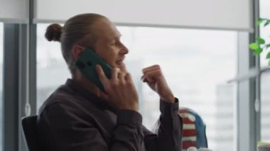 Neşeli iş adamı cep telefonunu kapalı yerde konuşuyor. Sözleşmeli başarı portresini dinleyen heyecanlı adam. Ofiste telefonla konuşan mutlu adam zafer kazandı. İş anlaşması konsepti