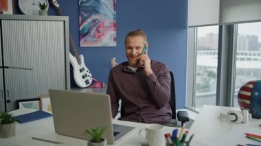 Ofiste cep telefonuyla konuşan gülen adam. Mavi Duvar 'ın ücra iş yerinden gelen neşeli bir acemi. Mutlu proje yöneticisi hipster apartmanında mola veren arkadaş konuşuyor. 