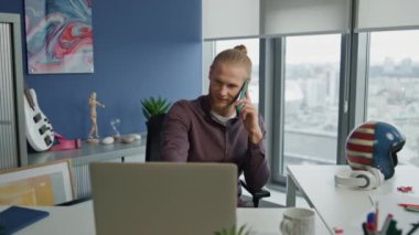 Sakin yönetici cep telefonundan ev telefonundan arıyorum. Uzaktan kumanda ofisindeki telefonu kullanarak işe başlamaya odaklanmış. Rahatlamış bir profesyonel olarak dizüstü bilgisayar ekranını seyrediyor. Yakışıklı iş adamı cep telefonunu dinliyor. 
