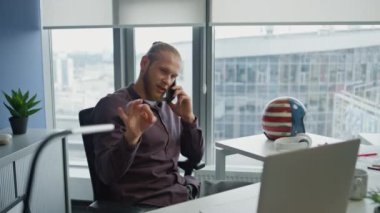 Ofiste cep telefonunu tartışan mutlu bir adam. İyi bir şirket ortamında el kol hareketi yapan olumlu girişimci akıllı telefon konuşuyor. Aşırı mutlu iş adamı, tek başına bilgisayardaki müşteriye cevap veriyor. 