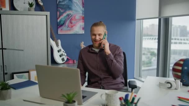 笑的家伙聊天手机在总公司关闭 快乐的创业者在蓝墙偏远的工作场所打电话 快乐的项目经理在嬉皮士公寓休息 — 图库视频影像