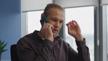 Uzaktan ofiste cep telefonuyla konuşan gergin bir adam. Stresli acemi, şehir manzaralı işyeri portresini arıyor. Duygusal proje yöneticisi hipster düz ana anları açıklıyor 