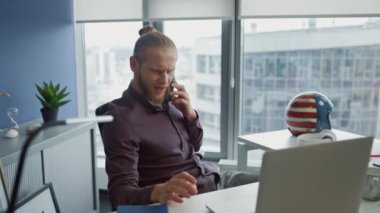 Ofiste yakın çekimde olumlu adam sohbeti. Akıllı telefondan konuşan genç bir adam kulağına cihaz dayamış. Uzaktan kumanda ofisindeki telefon anlaşmasını tartışan duygusal serbest çalışan. Modern teknoloji ve bağlantı