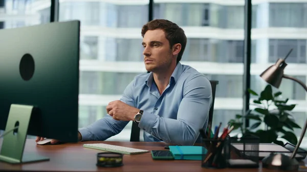 Sad office manager frustrated looking on computer monitor sitting at desk close up. Unhappy worker disappointed by corporate work results. Overworked man feeling exhausted tired on workplace.